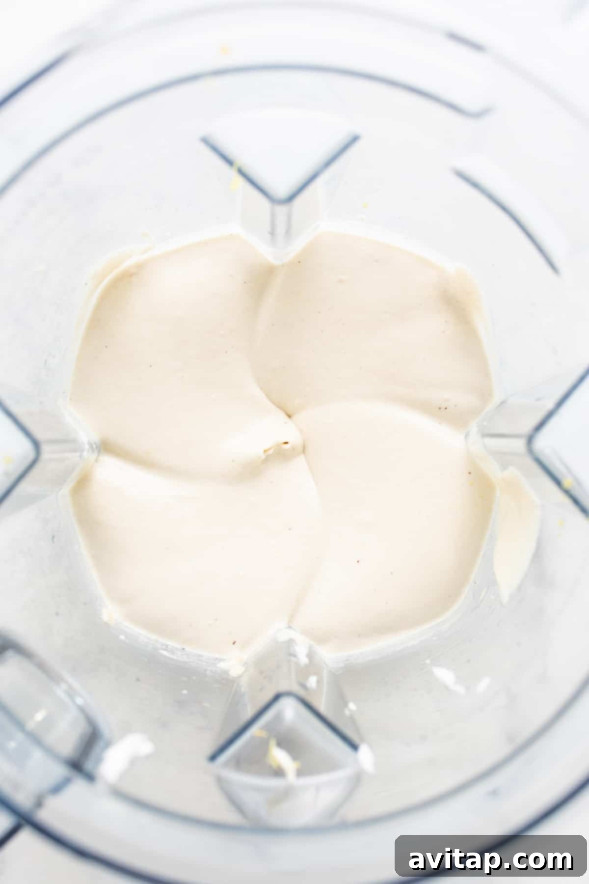 Effortless Vegan Cheesecake Bars 4 A high-speed blender containing the creamy, pale yellow vegan cheesecake filling, showcasing its smooth and lump-free consistency, ready to be poured over the crust.