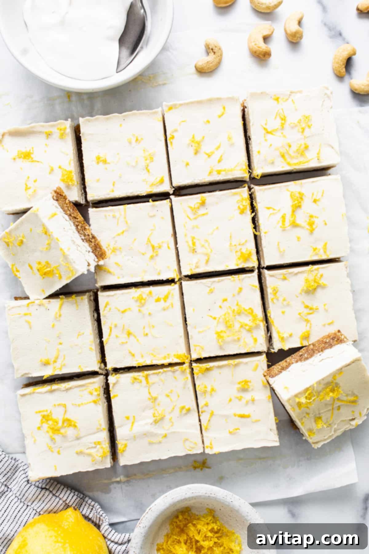 Effortless Vegan Cheesecake Bars 6 Close-up of a perfectly sliced lemon vegan cheesecake bar, topped with a dollop of fluffy cashew cream and a sprinkling of finely chopped cashews, ready to be enjoyed.