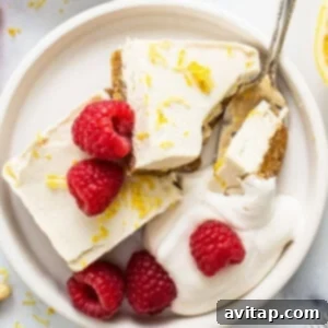 Effortless Vegan Cheesecake Bars 8 A plate with vibrant lemon vegan cheesecake bars and fresh raspberries on it, showcasing the final delicious dessert.