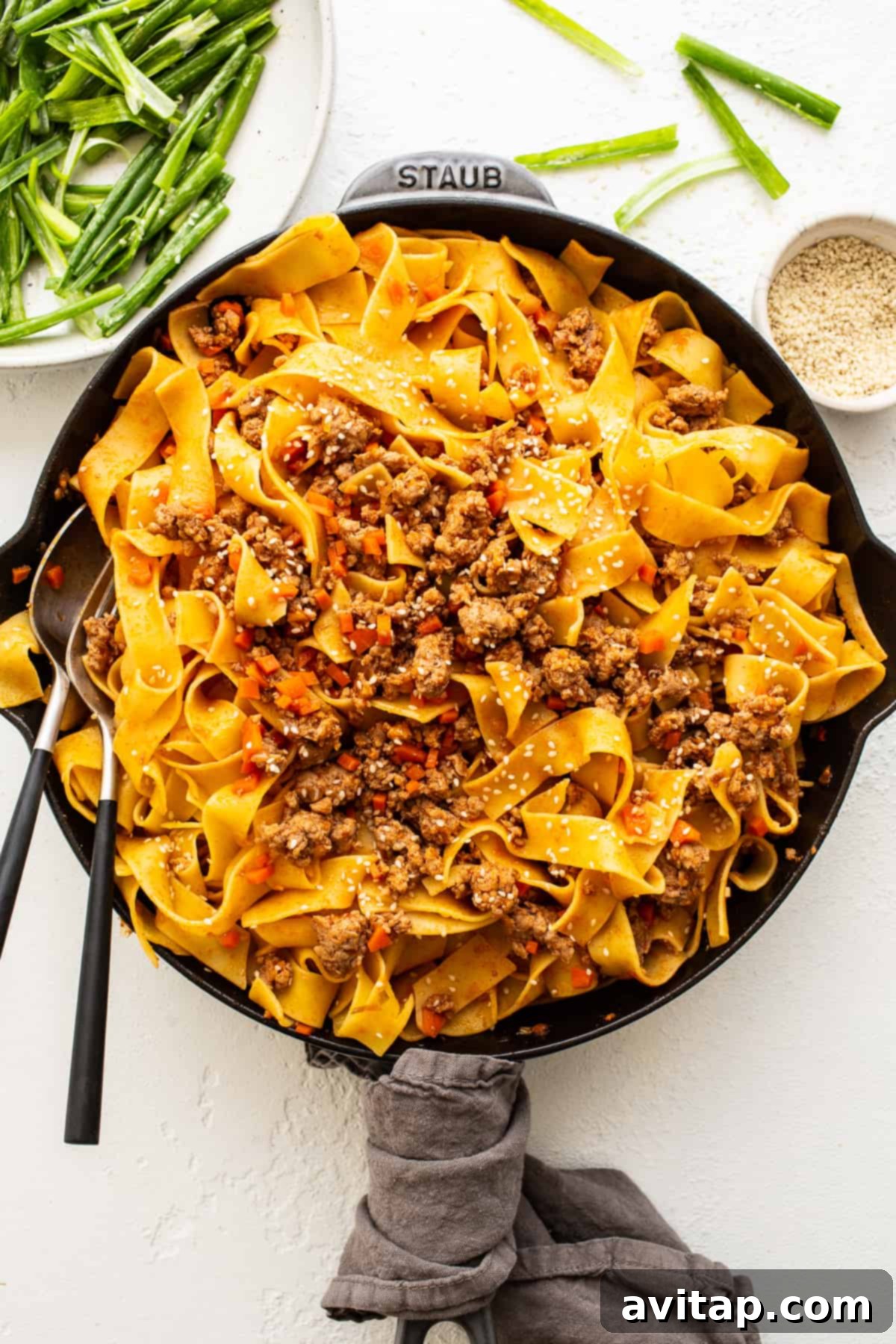 Spicy Gochujang Pork Noodles with Green Onion Salad A vibrant bowl of Gochujang Pork Noodles topped with fresh green onion salad and sesame seeds, ready to be enjoyed.