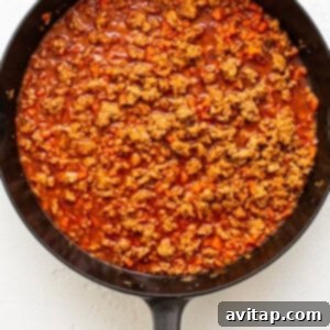 Weeknight Pork Noodles 7 A skillet with ground meat and vegetables coated in a rich, reddish-brown sauce.