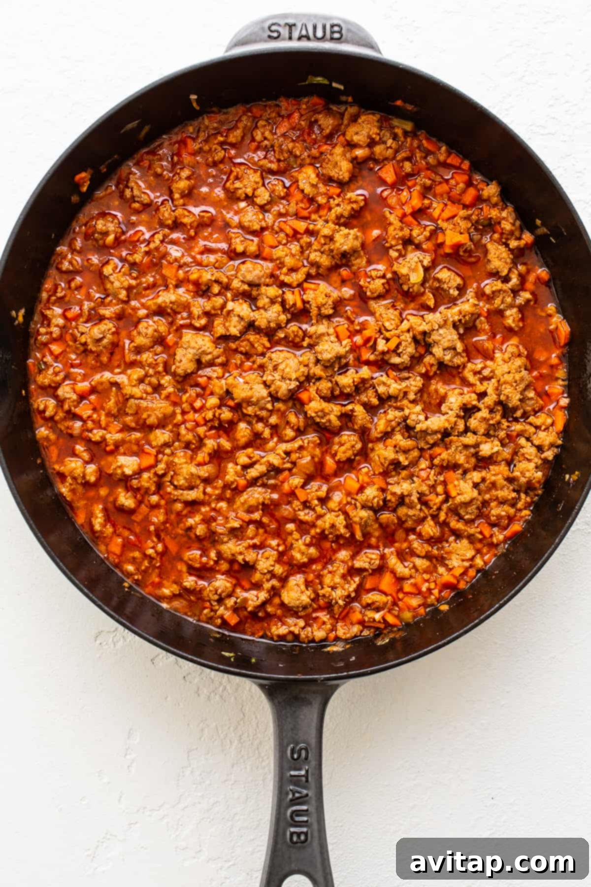 Saucy Pork Base for Gochujang Noodles Close-up of saucy gochujang pork cooking in a cast iron skillet, showcasing its rich texture and color.