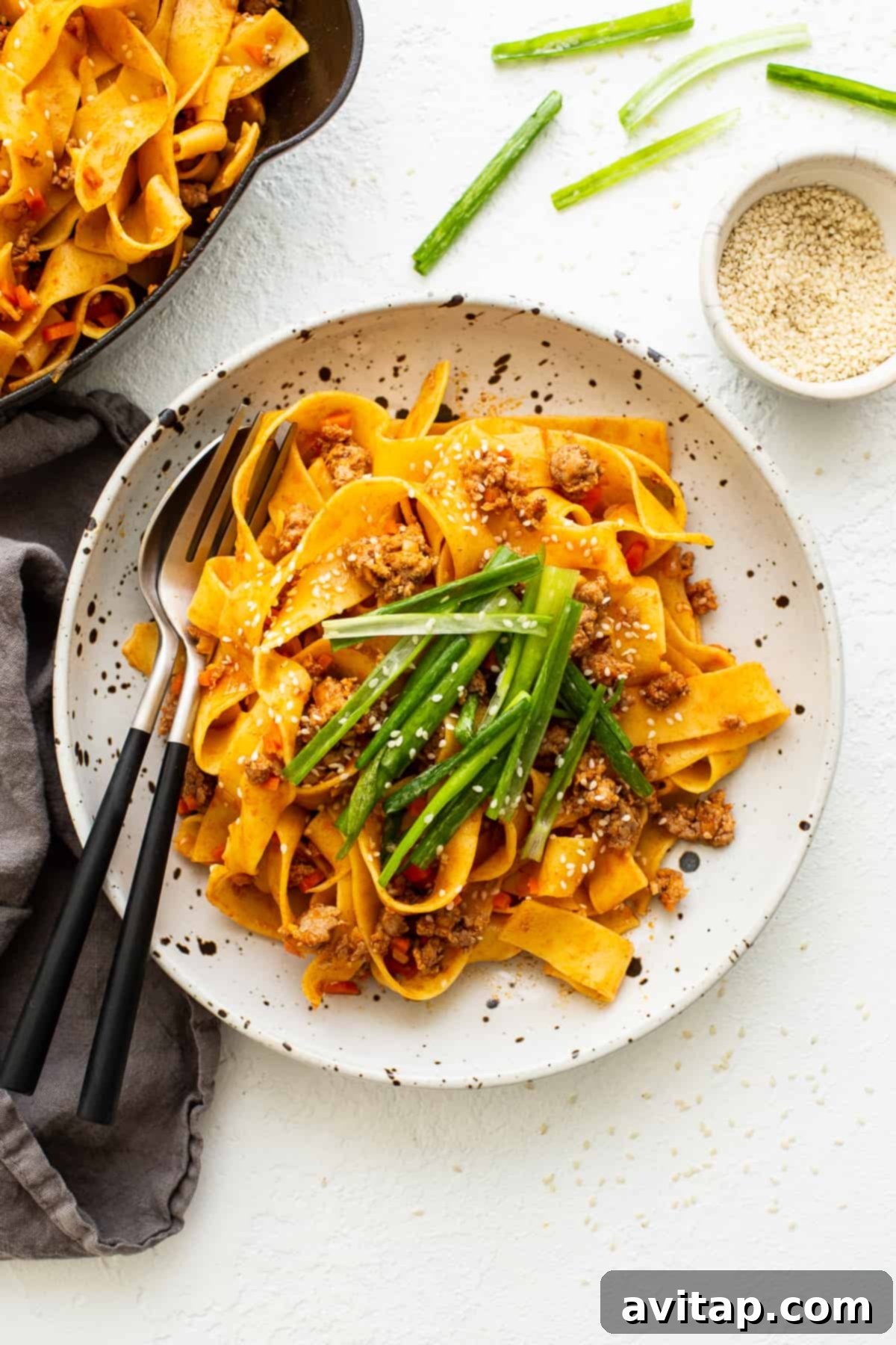 Ready-to-Serve Gochujang Pork Noodles A serving of Gochujang Pork Noodles garnished with green onion salad and sesame seeds, presented on a plate.