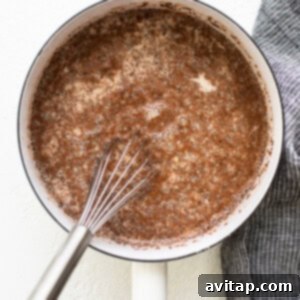 A frying pan with a whisk in it, combining oatmeal ingredients before cooking.