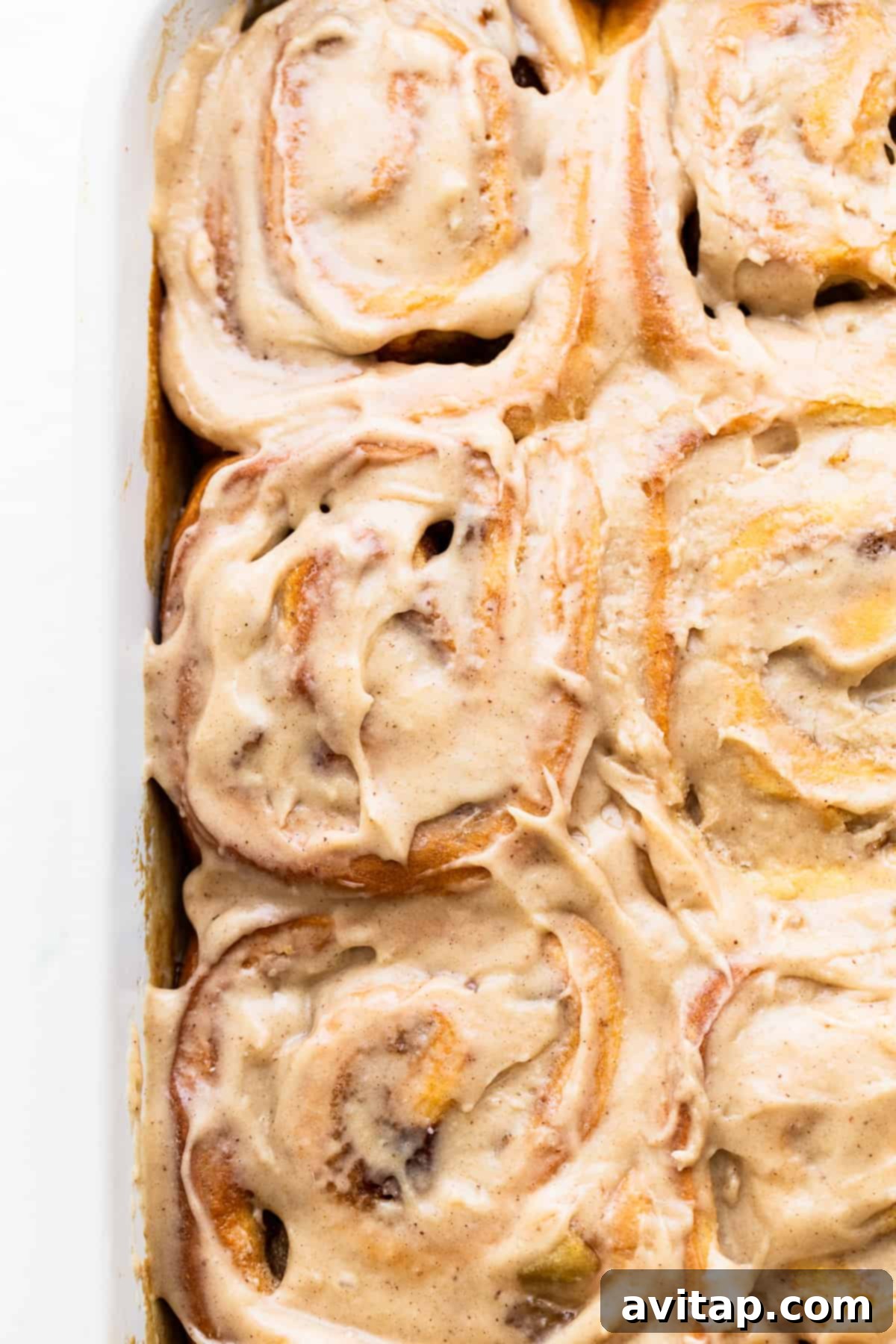 Warm apple cinnamon rolls with melted brown butter cream cheese frosting, served in a baking dish, ready to be enjoyed.