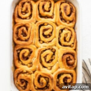 Baked cinnamon rolls in a white baking dish, fresh from the oven.