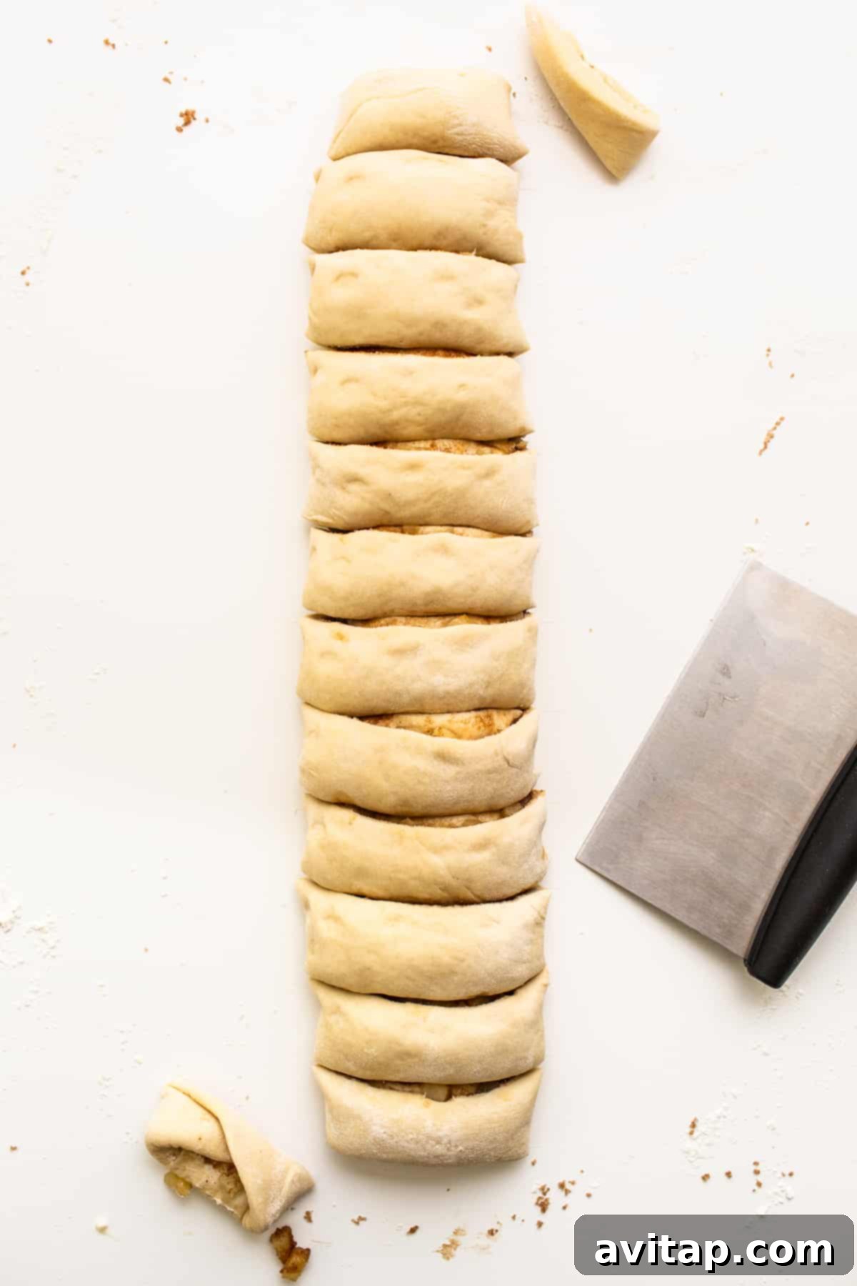 Apple cinnamon roll dough, neatly sliced into individual rolls, showcasing the beautiful spirals of filling and apples.