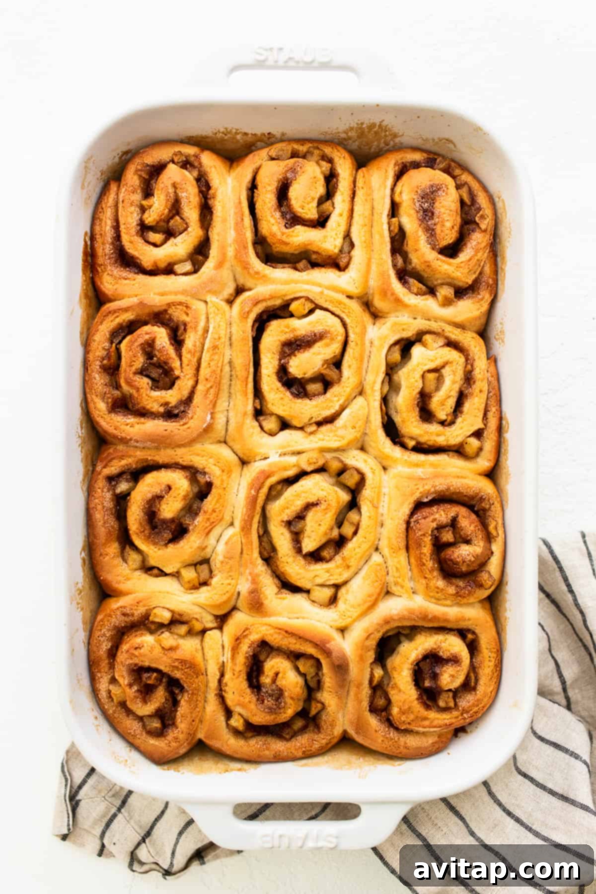 Freshly baked apple cinnamon rolls cooling in a casserole dish after being removed from the oven.