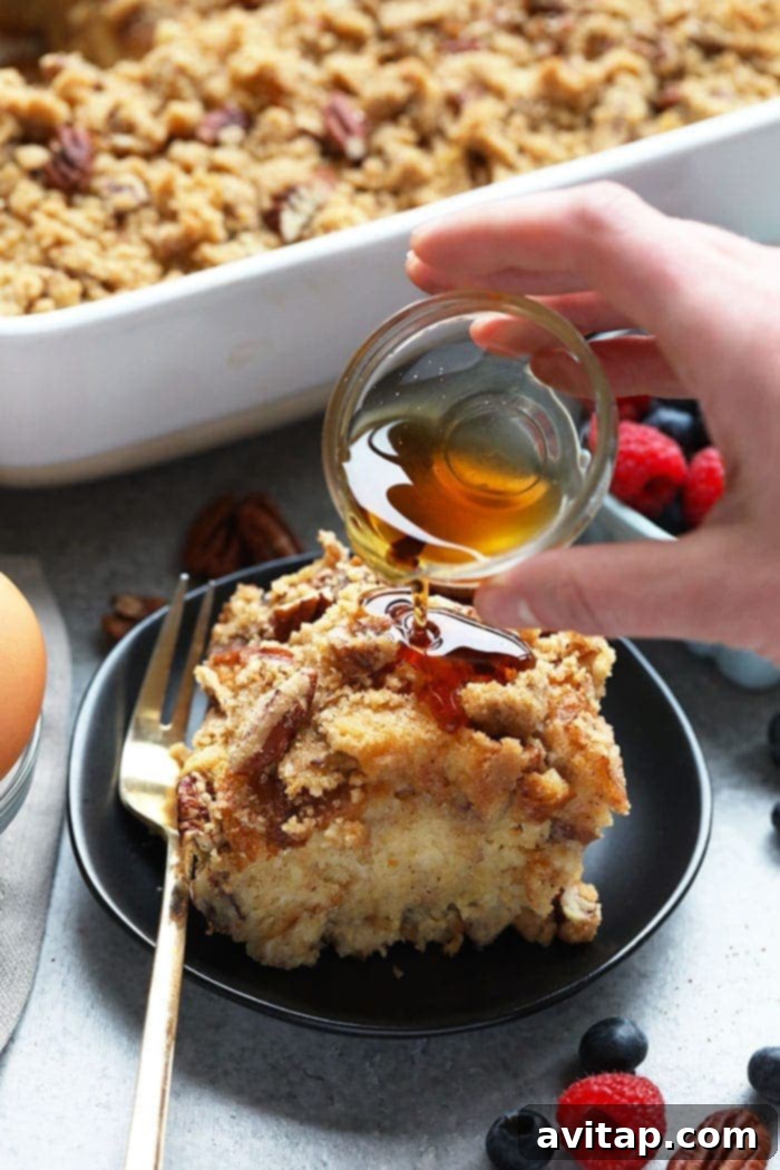 A delightful maple pecan overnight French toast bake, made with sourdough, being drizzled with syrup from above.