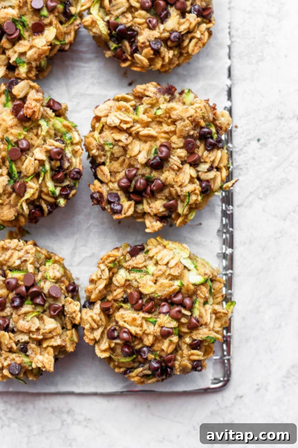 Individually baked chocolate chip zucchini oatmeal cups, showcasing their golden-brown tops and moist interior, served on a wire rack.