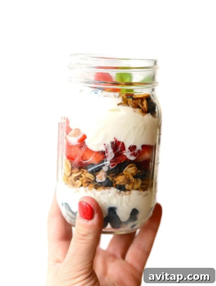 Beautifully layered yogurt and granola parfaits in mason jars, topped with fresh berries, ready for a healthy breakfast.