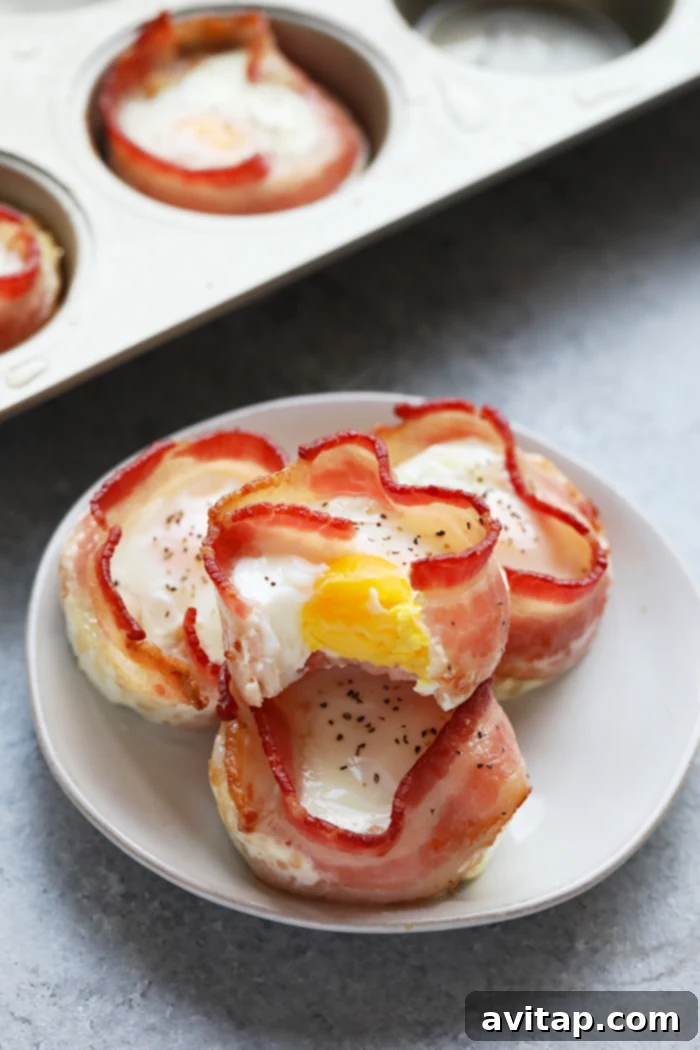 Perfectly baked bacon wrapped egg cups, garnished with fresh chives, arranged neatly on a serving plate.