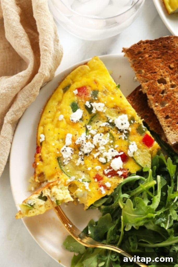 A freshly baked vegetable frittata, rich in colorful vegetables, served on a plate and ready to be enjoyed.