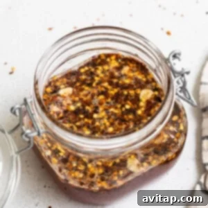 A jar of chili sauce with a spoon and a napkin, showing the cooled hot honey.