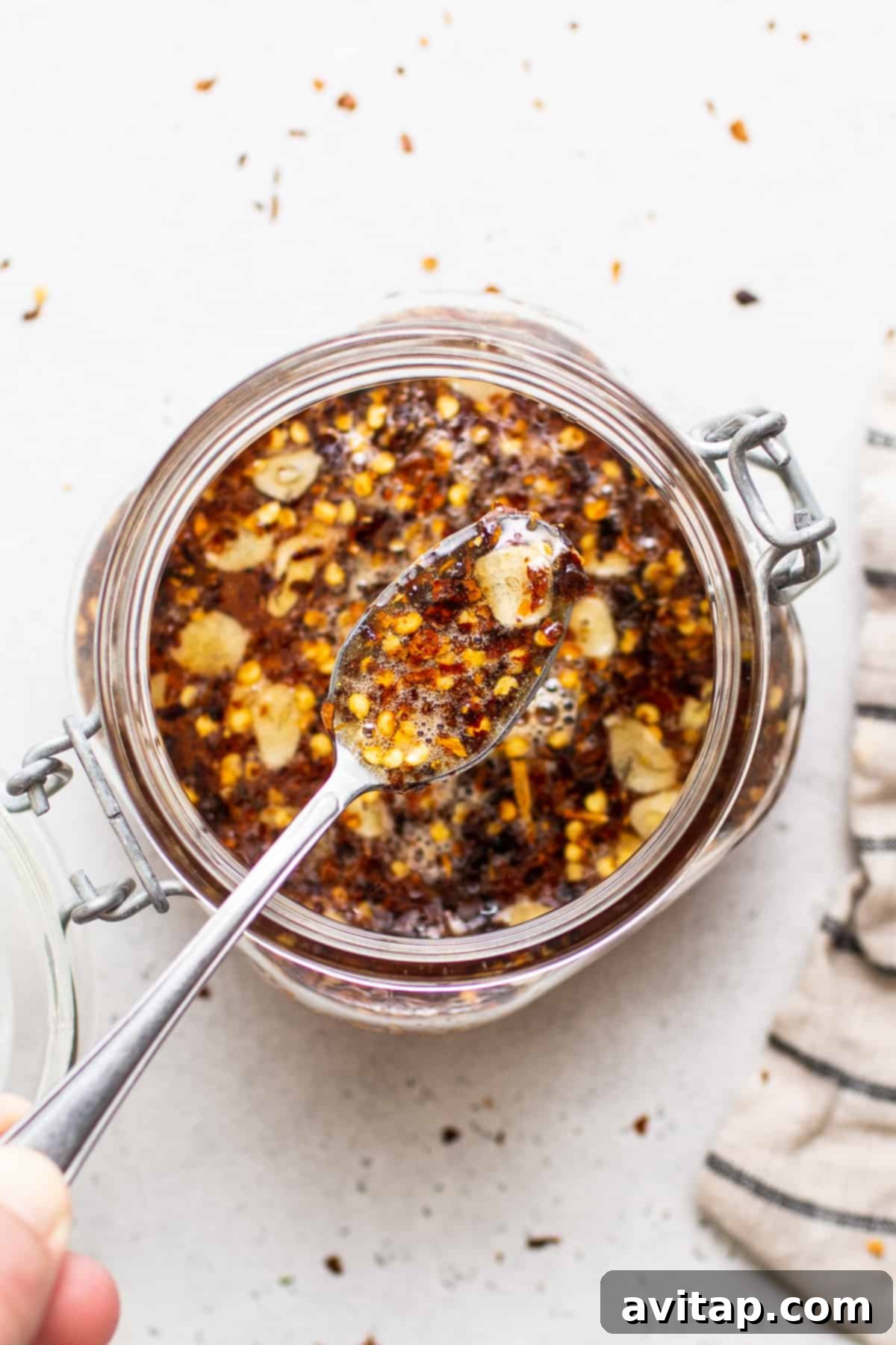 A mason jar filled with homemade hot honey sauce, showcasing its rich golden color and suspended chili flakes, ready for storage or serving.