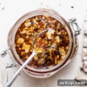 Hot honey sauce in a small bowl, garnished with chili flakes and a drizzle spoon, ready to serve.