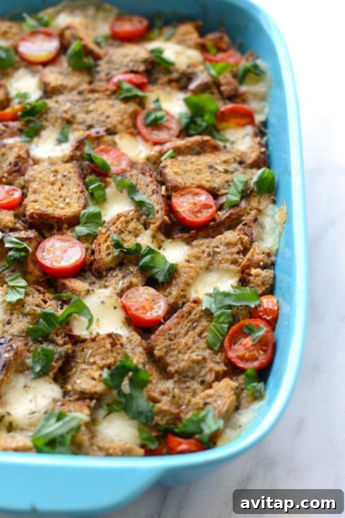 A top-down view of the Caprese Egg Bake, showcasing its perfectly golden-brown top, gently bubbling melted cheese, and the vibrant red tomatoes and green basil elements. The casserole is ready to be sliced and served for a savory meal.