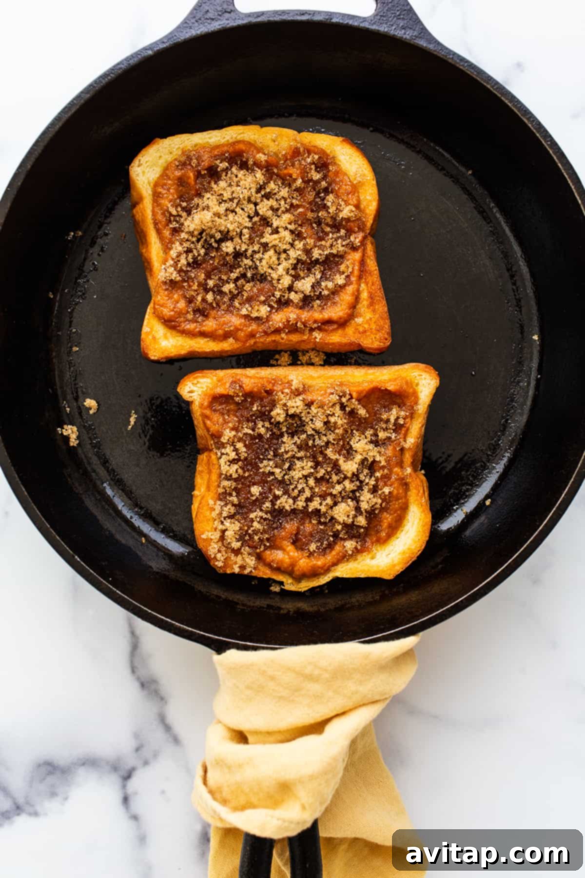 Pumpkin Creme Brûlée French Toast in a Skillet A golden-brown slice of Pumpkin Creme Brûlée French Toast resting in a cast iron skillet, fresh out of the oven.