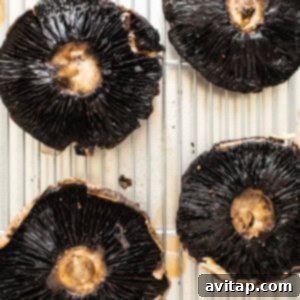 Portobello mushrooms on a baking sheet, seasoned and ready for par-baking.