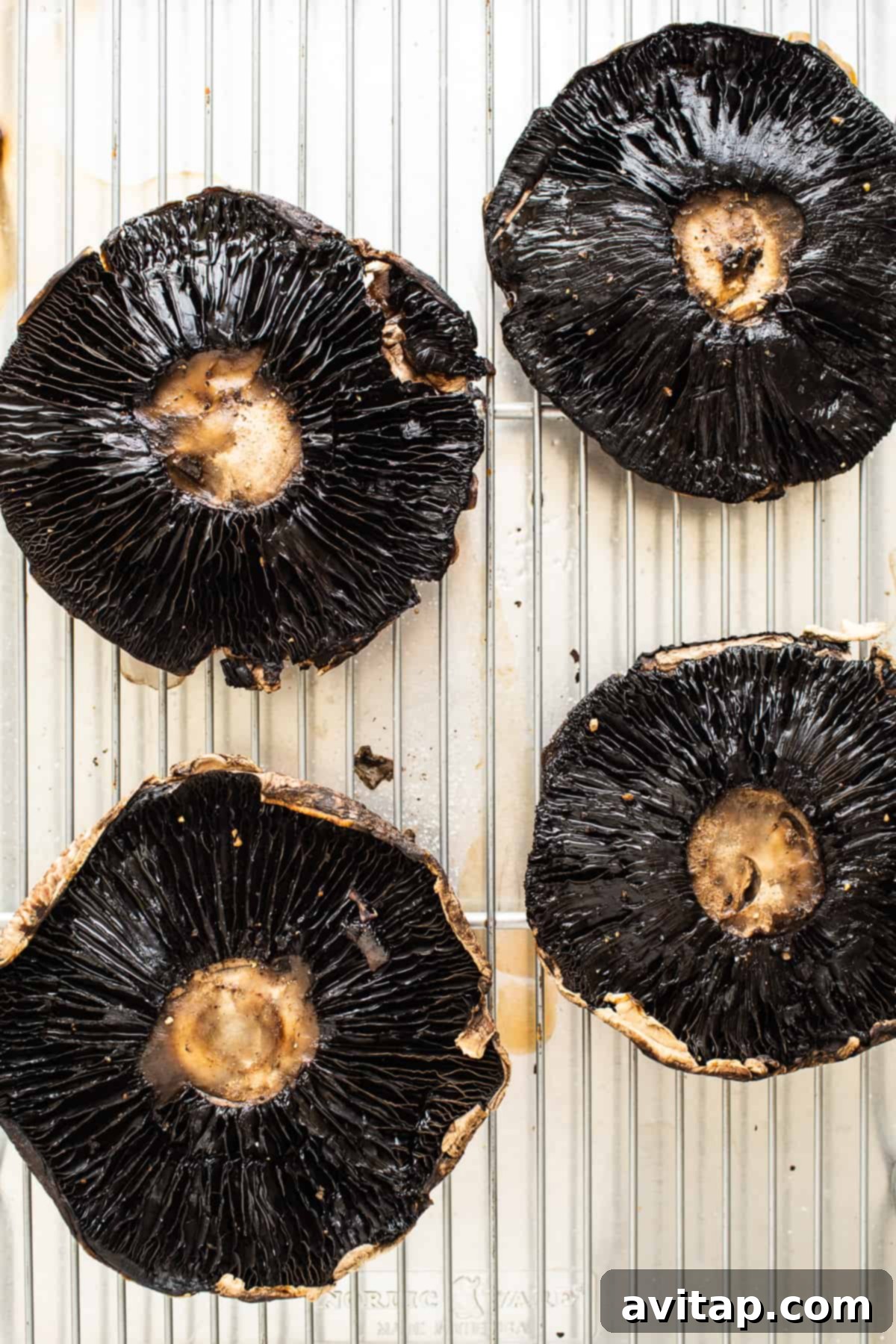 Savory Stuffed Portobello Caps 3 Portobello mushrooms arranged on a baking sheet with a wire rack, ready for par-baking.