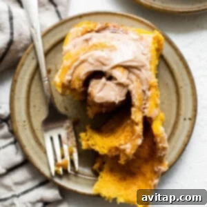 Spiced Pumpkin Cinnamon Rolls 4 A square image of a baked pumpkin cinnamon roll covered with frosting.