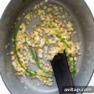 Diced white onion being sautéed in a large Dutch oven.