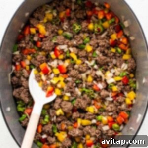 Ground beef, peppers, and onions sautéing in a pot.
