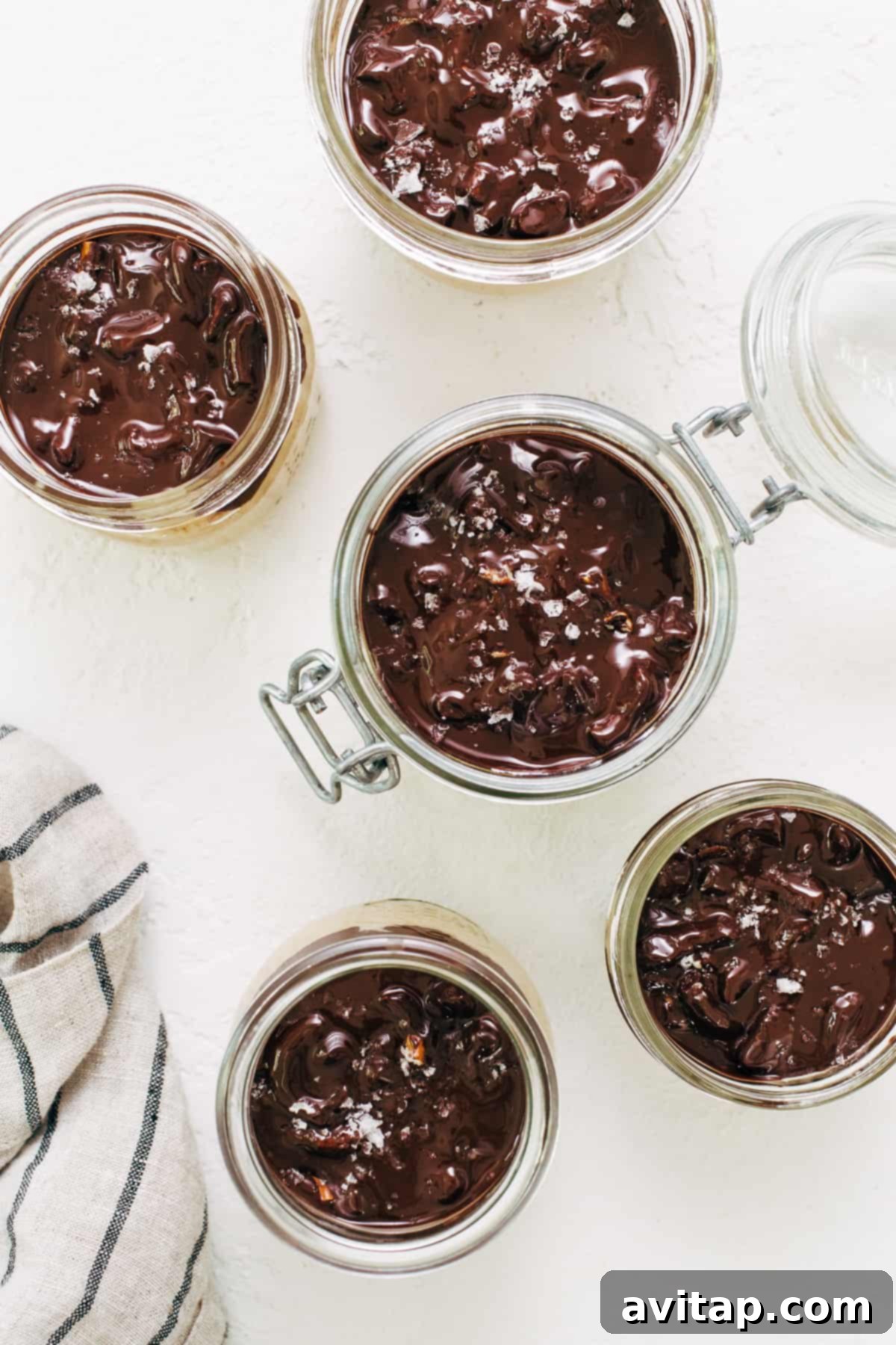 Six individual servings of pumpkin mousse in mason jars, topped with the hardened chocolate pretzel topping and ready to serve.