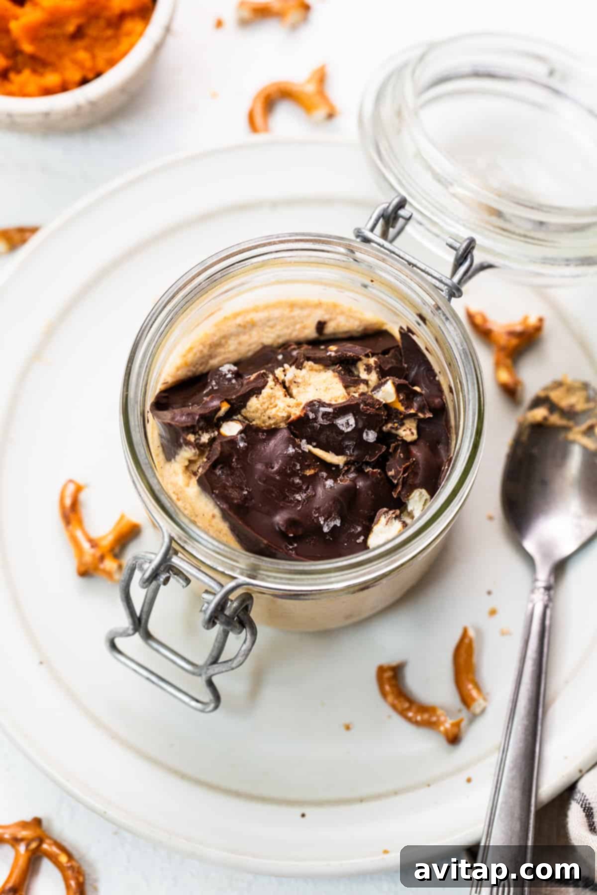A single jar of pumpkin mousse with its distinct layers, ready to be chilled or served, highlighting the chocolate pretzel topping.