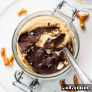 Pumpkin mousse in a glass jar, topped with a dark chocolate and pretzel crunch, ready to be served.