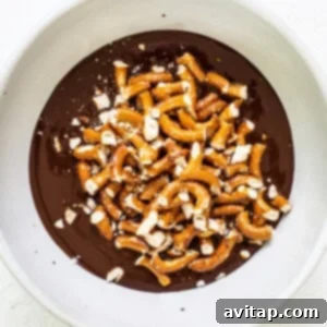A white bowl filled with chocolate and pretzels.