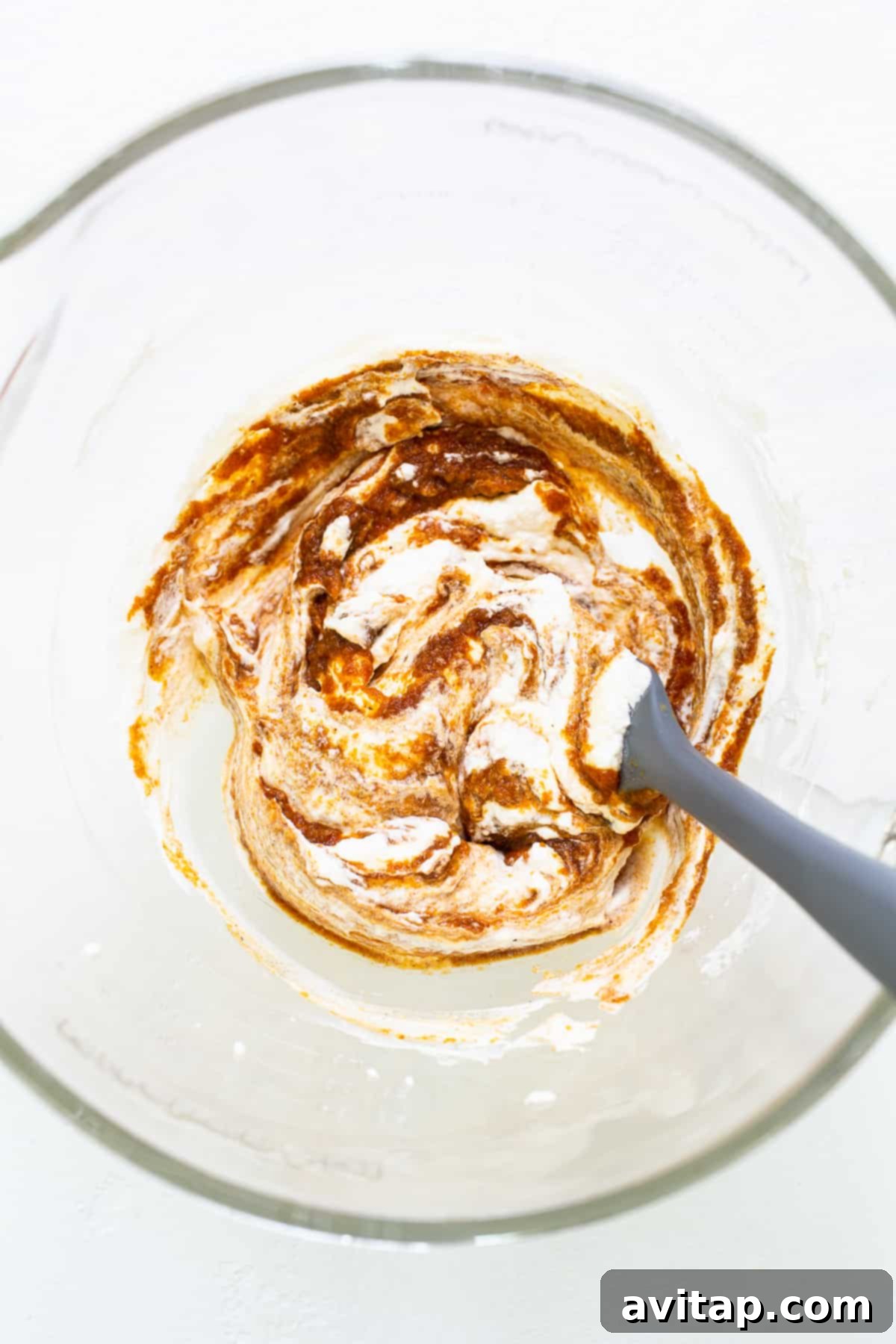 The pumpkin mixture being gently folded with fluffy whipped cream in a bowl, creating a light, airy, and delicately orange mousse base.