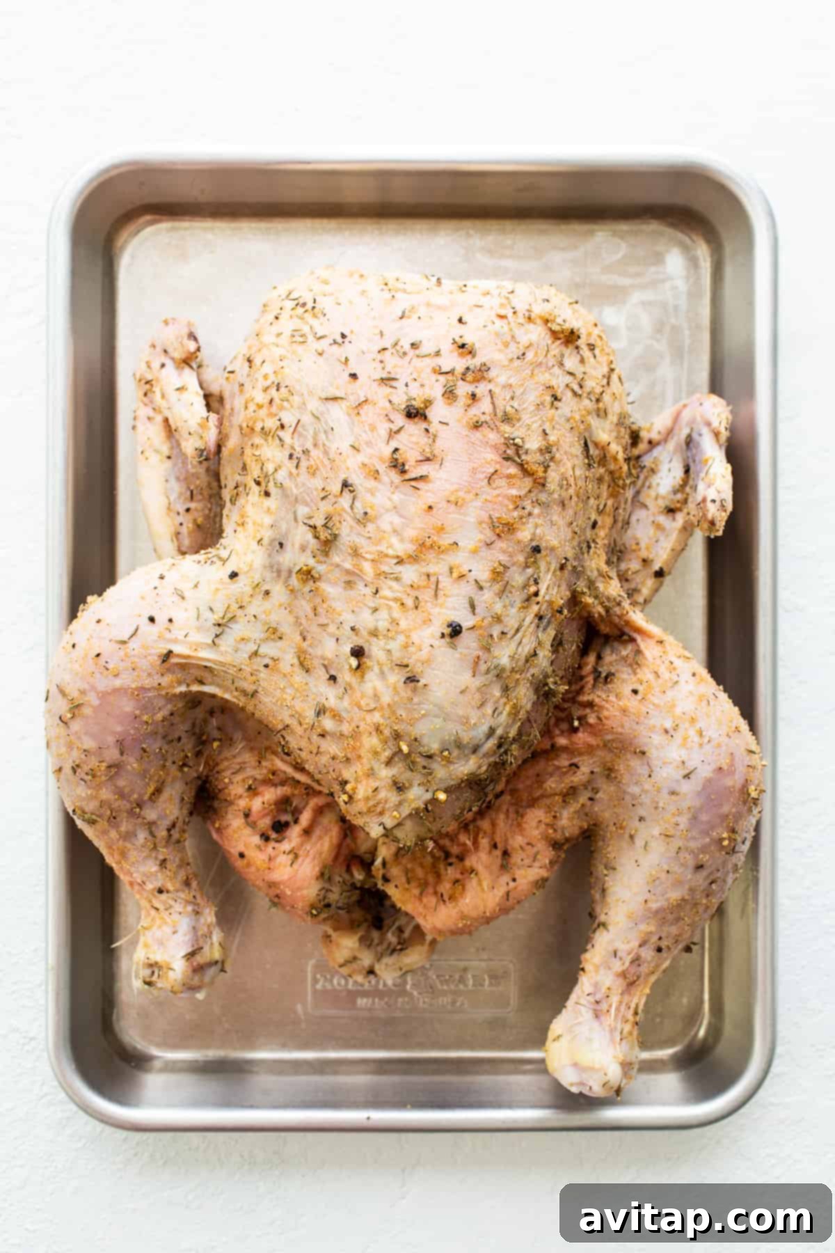 Seasoned Whole Chicken for Instant Pot A generously seasoned whole chicken resting on a sheet pan, its skin glistening with herbs and spices, ready for its Instant Pot transformation.