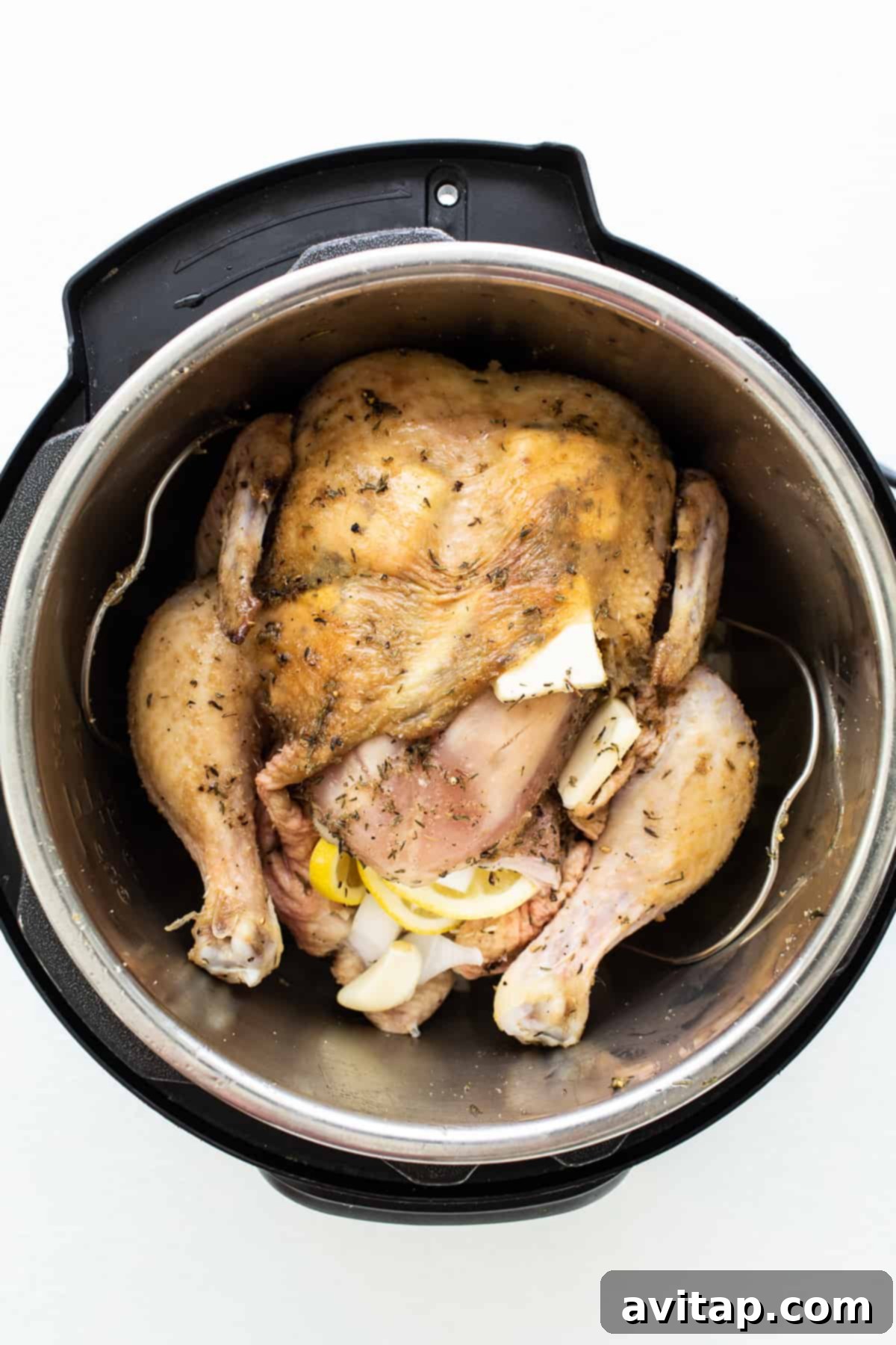 Instant Pot Whole Chicken Ready for Pressure Cooking A raw whole chicken stuffed with lemons, onions, and garlic, sitting on a metal trivet inside the Instant Pot before cooking, demonstrating proper setup.