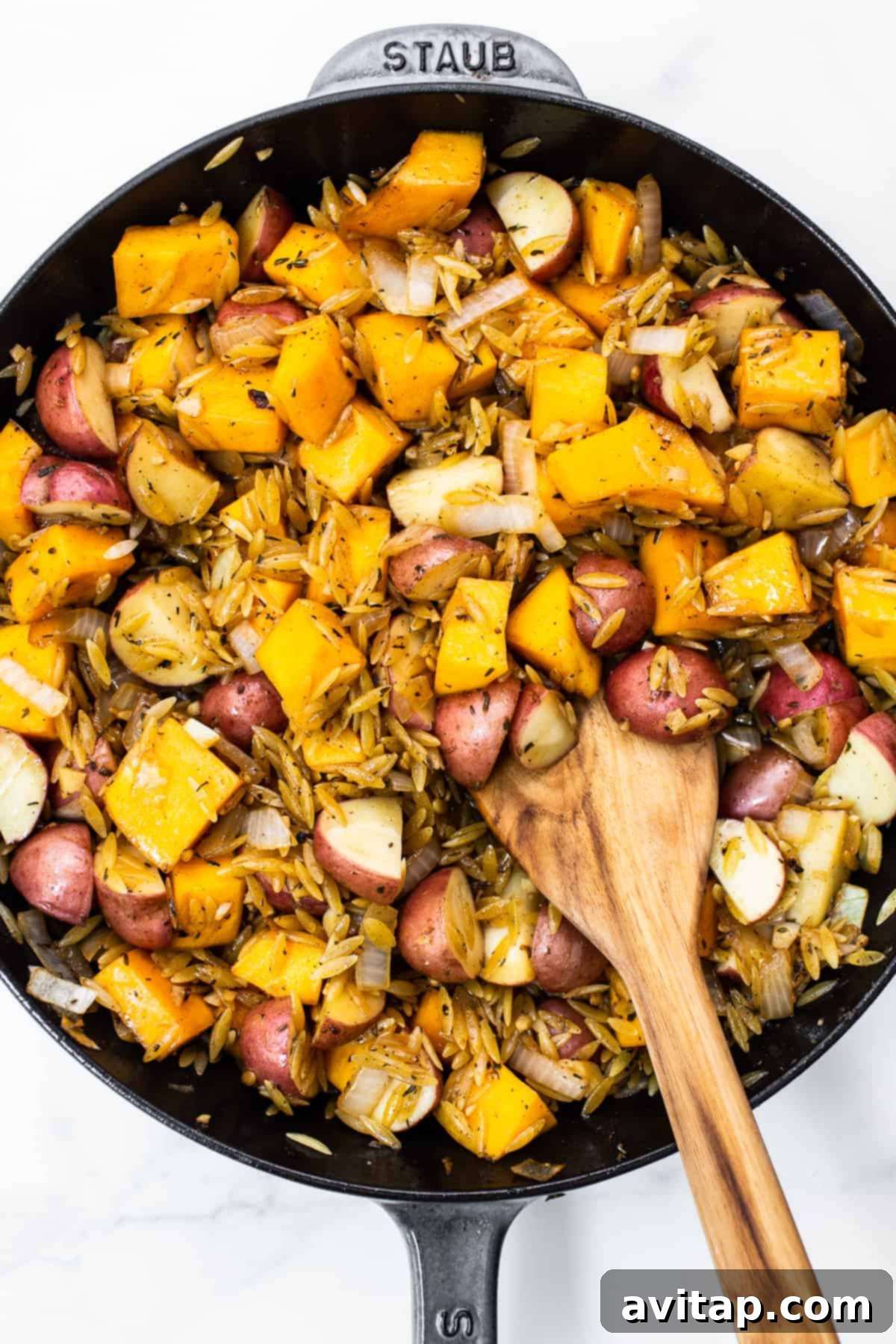 One-Pan Harvest Orzo Dinner 7 A close-up of orzo, butternut squash, and red potatoes simmering in a cast iron skillet before baking.
