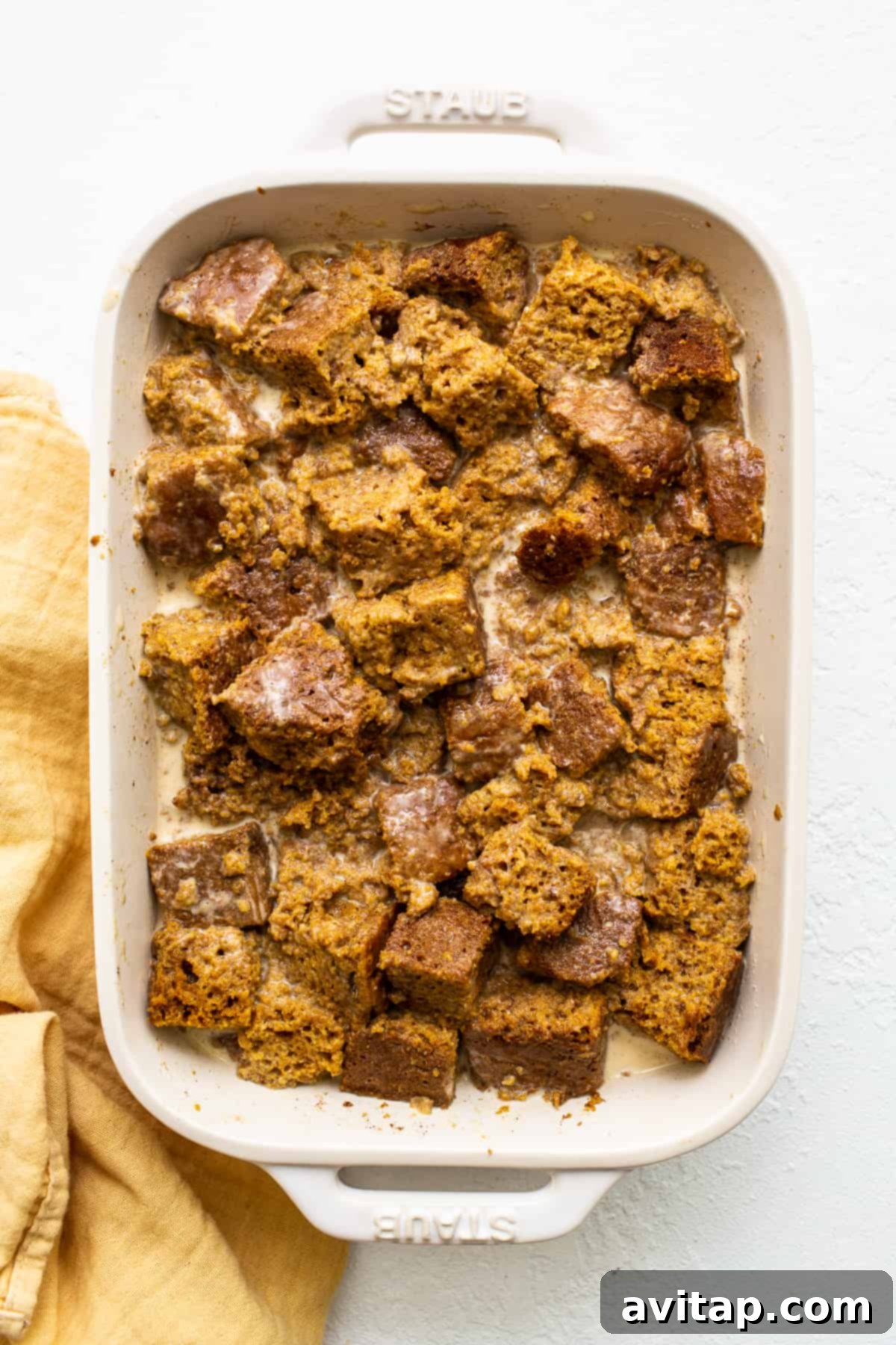 Uncooked pumpkin bread pudding in a casserole dish, topped with a pecan streusel before baking.