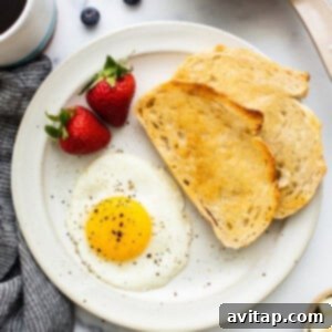A finished sunny side up egg on a plate with salt and pepper.