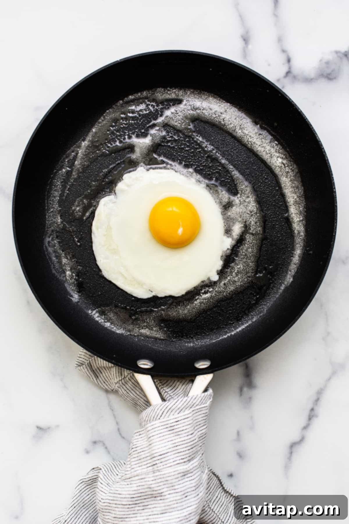 A single perfectly cooked egg resting in a nonstick pan.