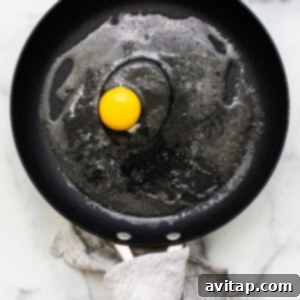 A cracked egg settling in a pan.