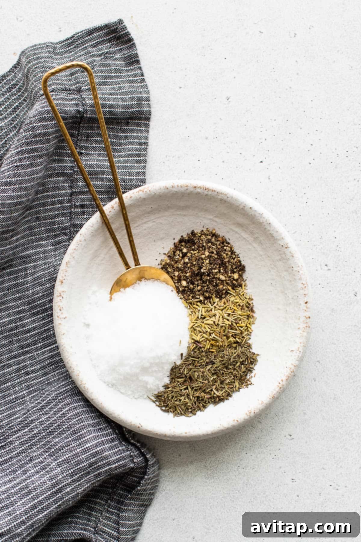 A small white bowl filled with a fragrant mixture of kosher salt, black pepper, dried thyme, and dried rosemary, ready for the turkey.