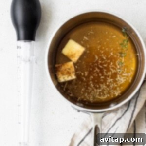 A pot of simmering basting liquid with a spoon resting inside.