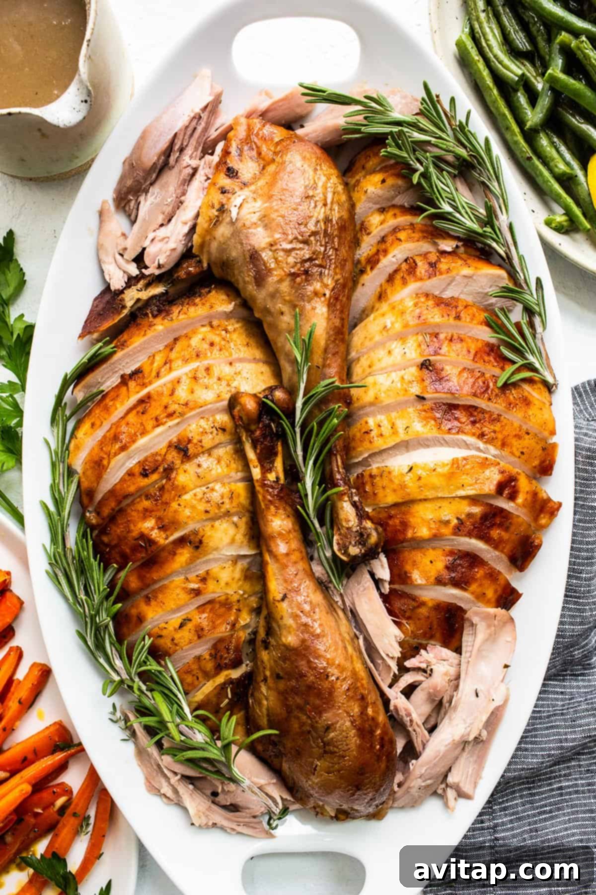 Juicy Thanksgiving turkey, perfectly sliced and arranged on a platter with herbs, ready for serving.