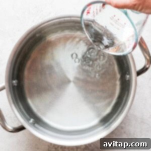 Adding water to a large brining pot, the initial step for preparing turkey brine.