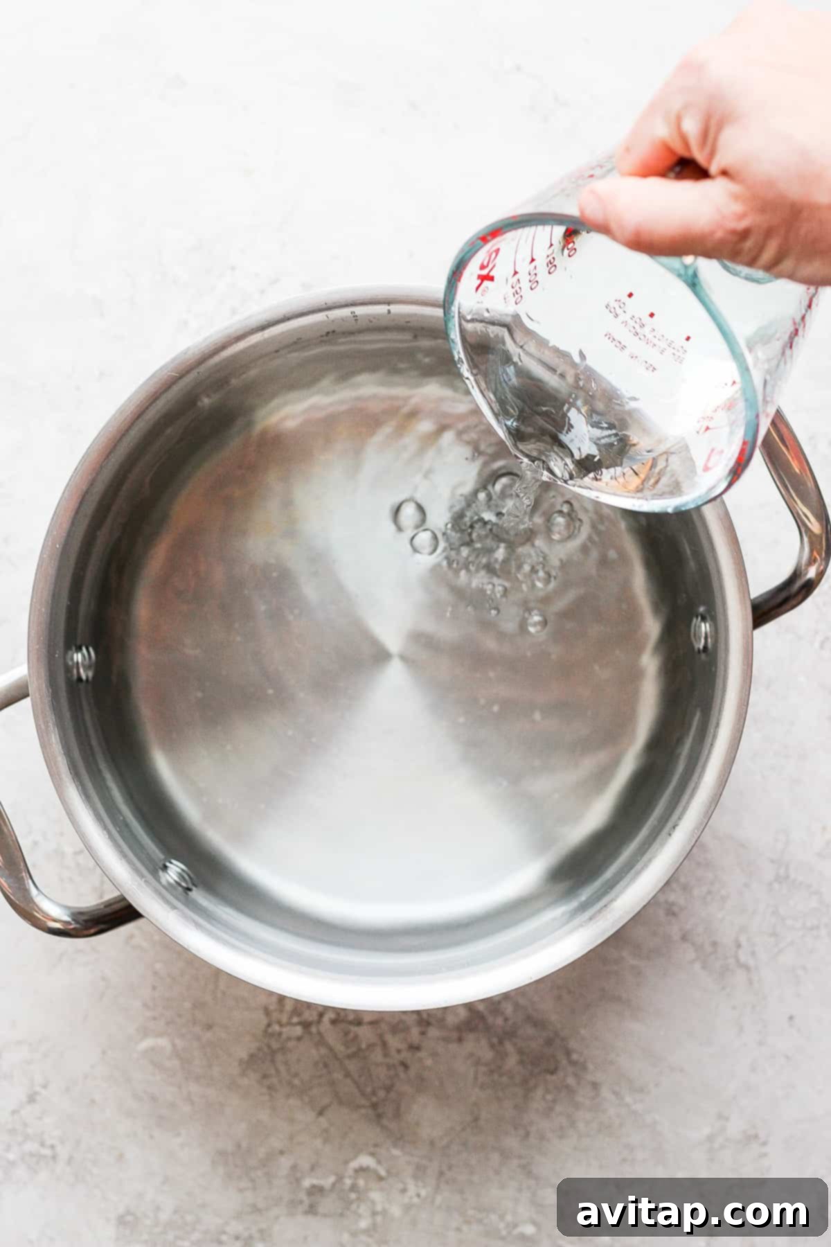 Adding water and spices to a large pot for a wet brine mixture.