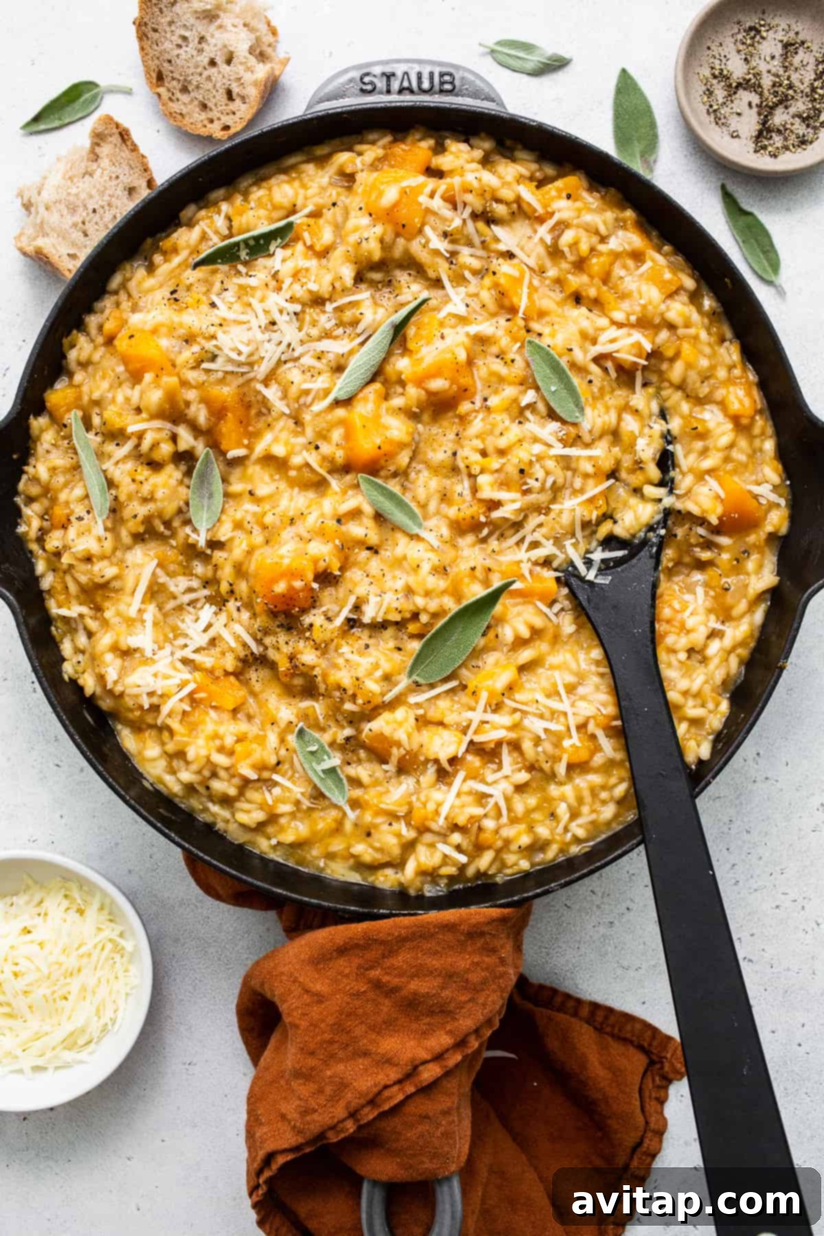 Hands stirring a pot of creamy butternut squash risotto on a stovetop, highlighting the cooking process.