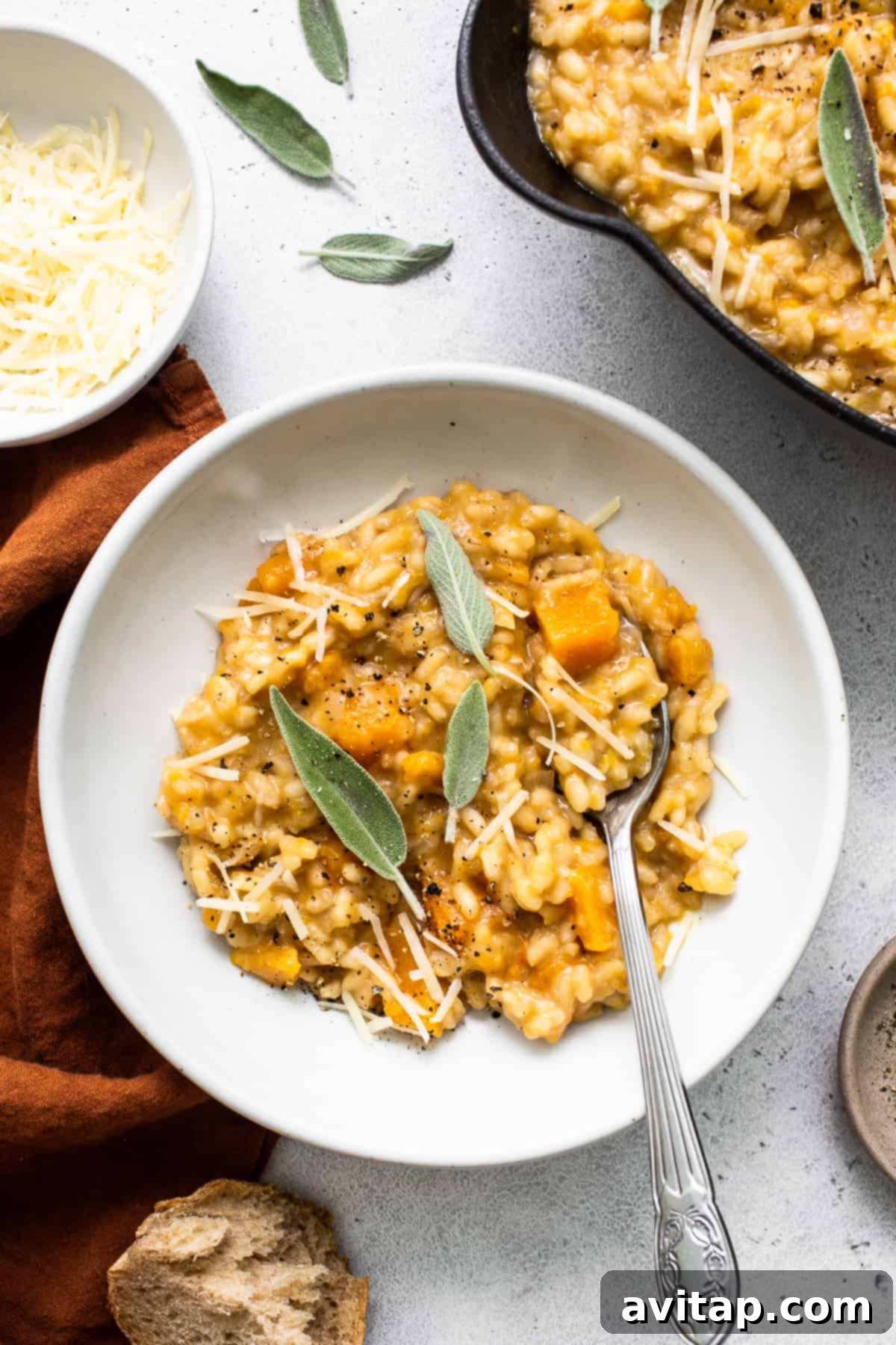 A vibrant bowl of butternut squash risotto, perfectly garnished, next to a spoon, inviting enjoyment.