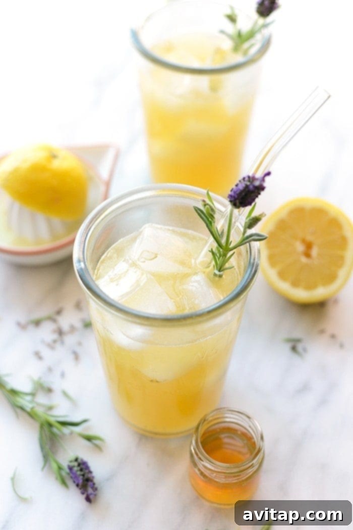 Honey Lavender Lemonade: Natural Sweetness & Floral Notes Honey Lavender Lemonade in a glass, with dried lavender flowers and a small jar of honey in the background, showcasing natural ingredients.