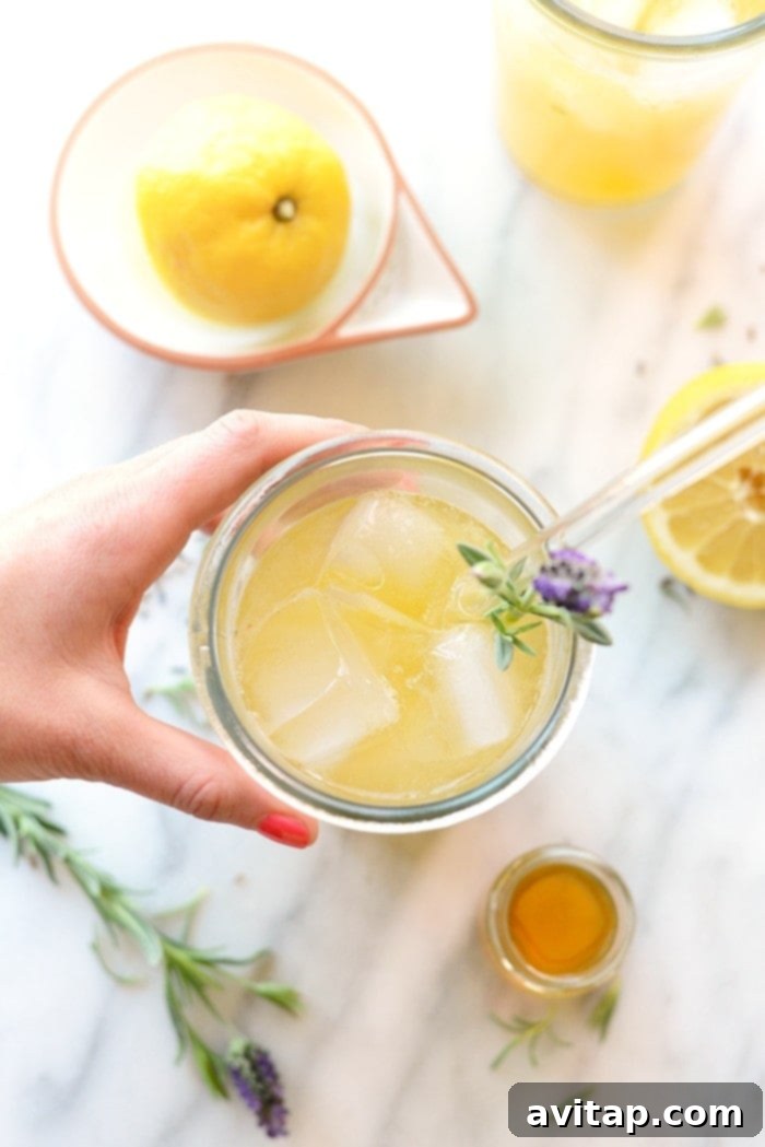 Iced Honey Lavender Lemonade: A Perfect Summer Refreshment Close-up of a glass of refreshing Honey Lavender Lemonade with ice cubes and a lemon slice, ready to be enjoyed on a hot day.