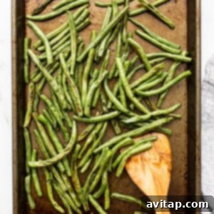 Freshly roasted green beans on a baking sheet, ready for the final lemon juice toss and serving.
