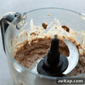 Food processor creating a smooth and creamy black bean mash for delicious breakfast burritos.